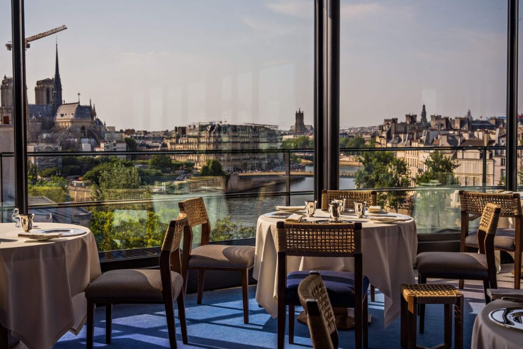 Elegant fine dining restaurant overlooking the city with beautifully dressed tables prepared for an upscale dinner service.
