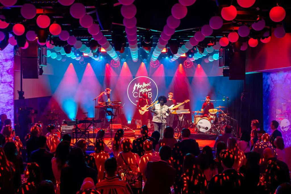 Live jazz band performing on stage inside an intimate jazz club with guests enjoying the evening.