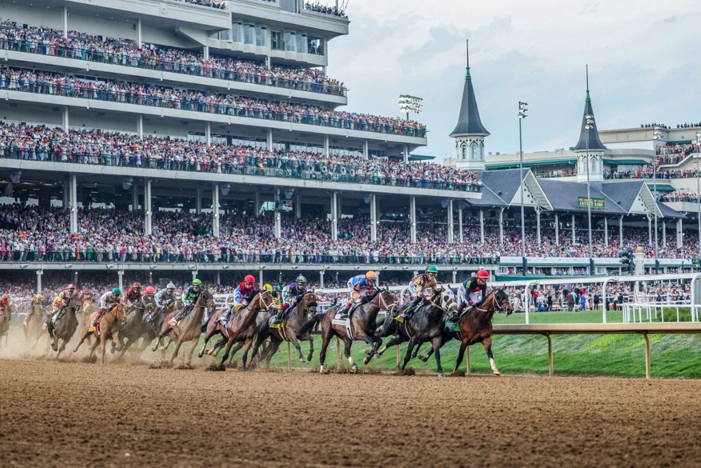 Horses racing in front of packed grandstands at Churchill Downs during the Kentucky Derby.