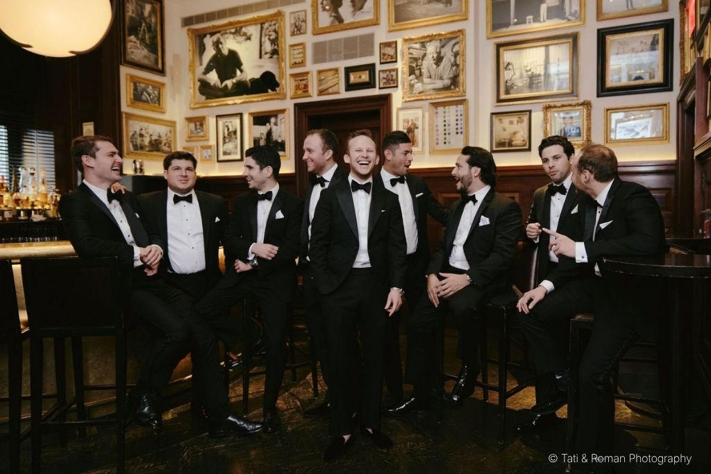 Groomsmen in black tuxedos at an elegant black tie wedding reception.