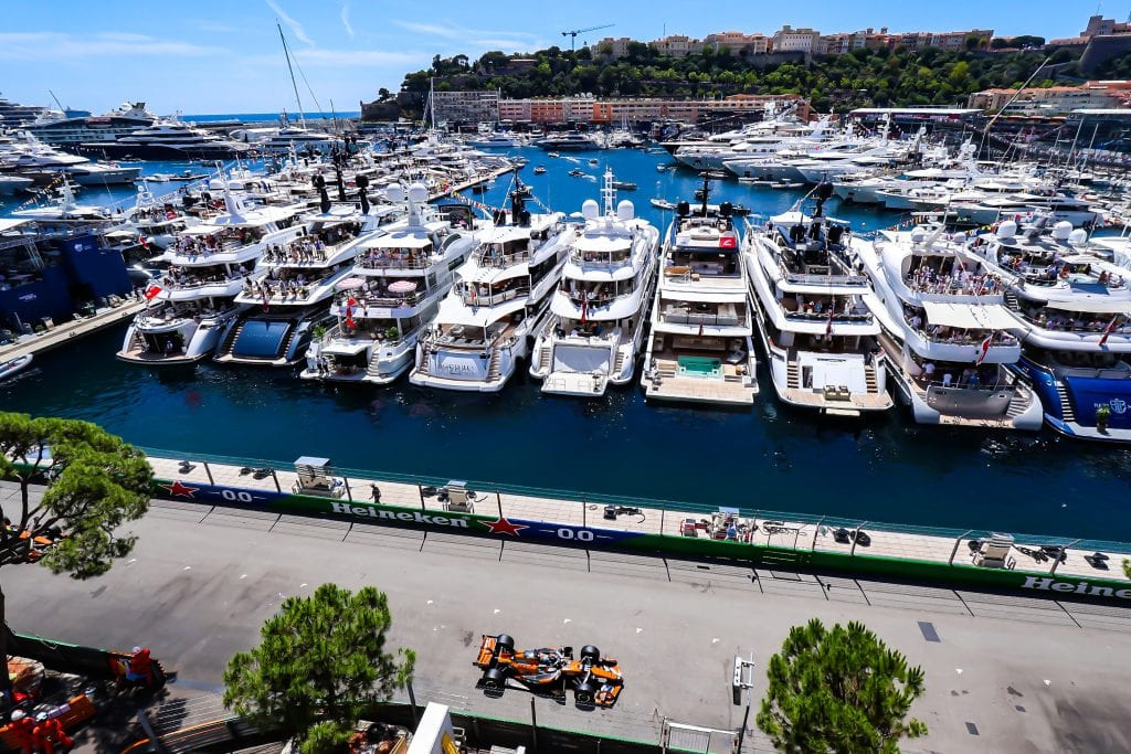 Formula One car racing past luxury yachts in Monaco harbour during the Monaco Grand Prix.