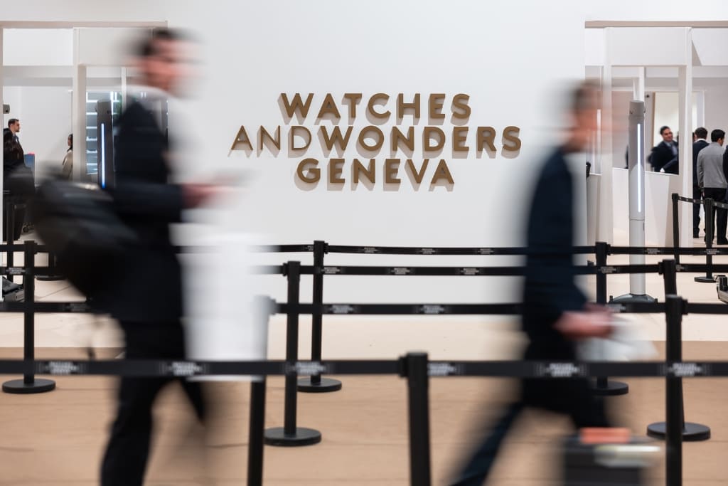 Visitors walking through the entrance area of Watches and Wonders Geneva, with the event logo displayed in the background.