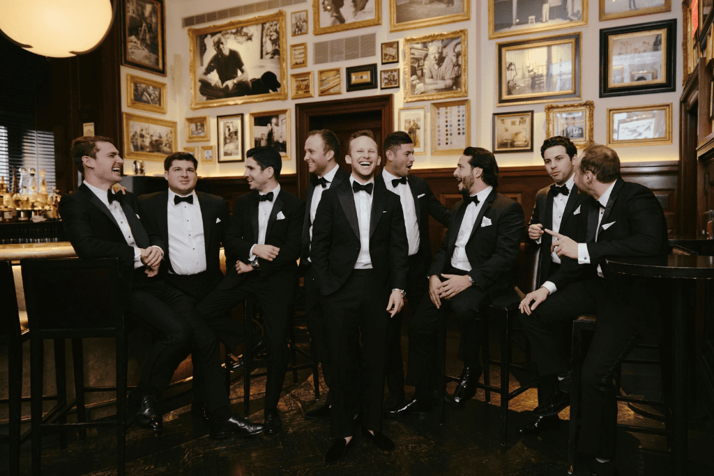 Groomsmen in black tuxedos at an elegant black tie wedding reception.