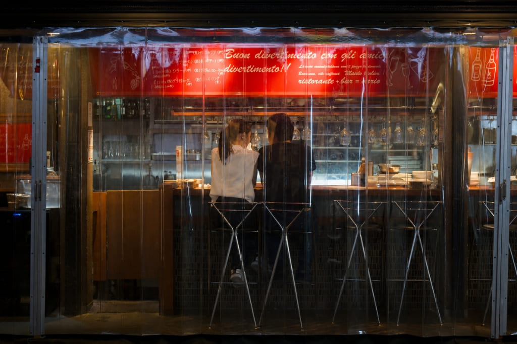 Couple sitting together at a softly lit restaurant bar, seen through the window during a first date.