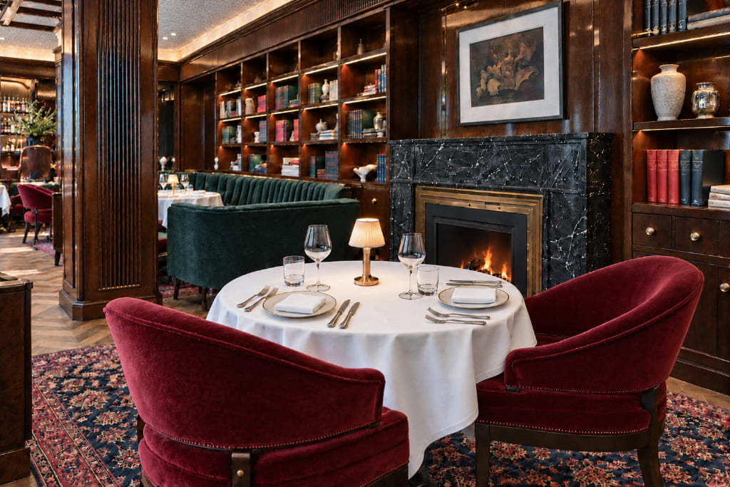 Intimate anniversary dinner table set beside a fireplace in an elegant restaurant.