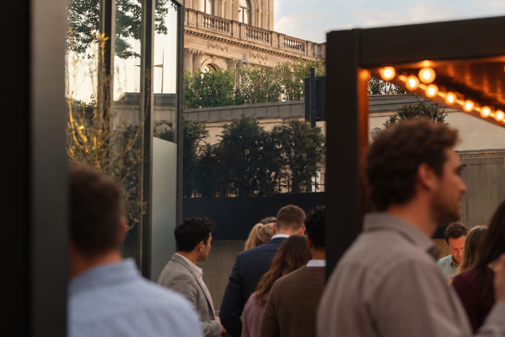 Networking event with professionals socialising at an evening reception in a modern indoor-outdoor venue.