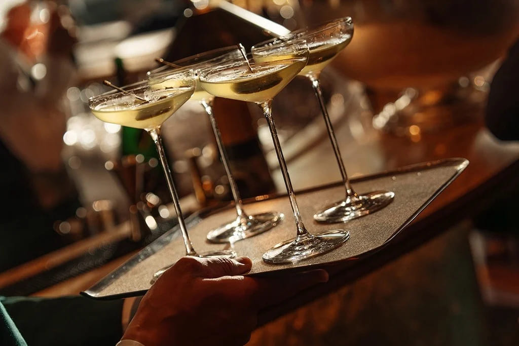 Cocktail drinks served on a tray at an evening party or reception.
