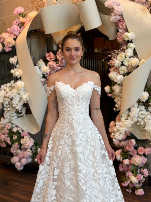 Modern bride wearing an off the shoulder satin wedding gown with structured bodice
