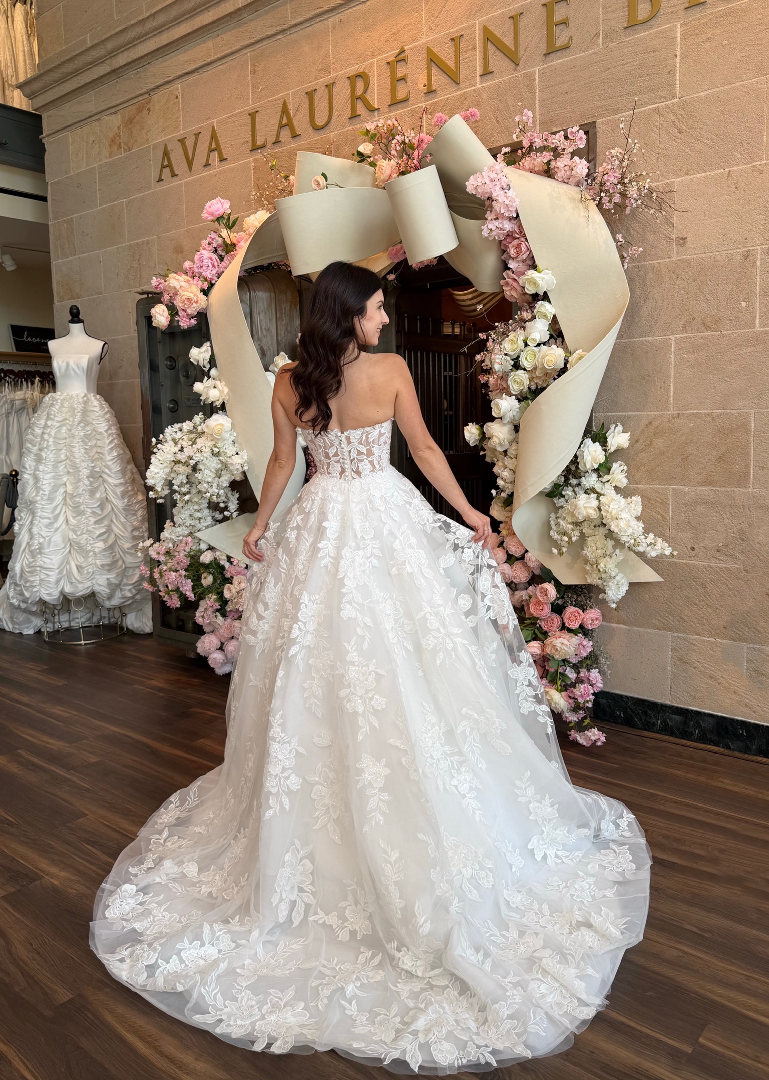 Bride wearing a floral lace A line wedding gown with off the shoulder sleeves at Ava Laurénne Bride in Fredericksburg Virginia.