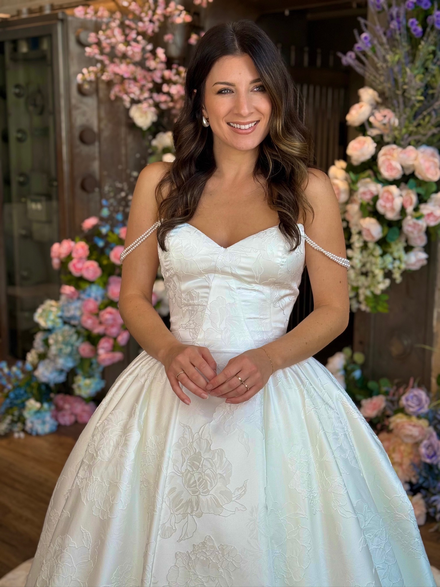 Bride modeling a dramatic off the shoulder ball gown wedding dress with sparkling embellishments