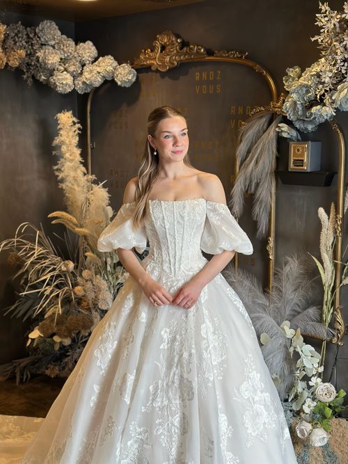 Statement off the shoulder wedding gown with dramatic volume and luxurious lace embellishments