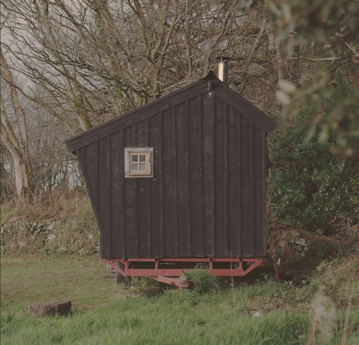 Gable end of asymmetric black wooden cabin in the woods