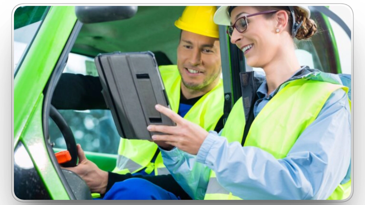 Construction workers reviewing fleet data on a tablet inside heavy equipment