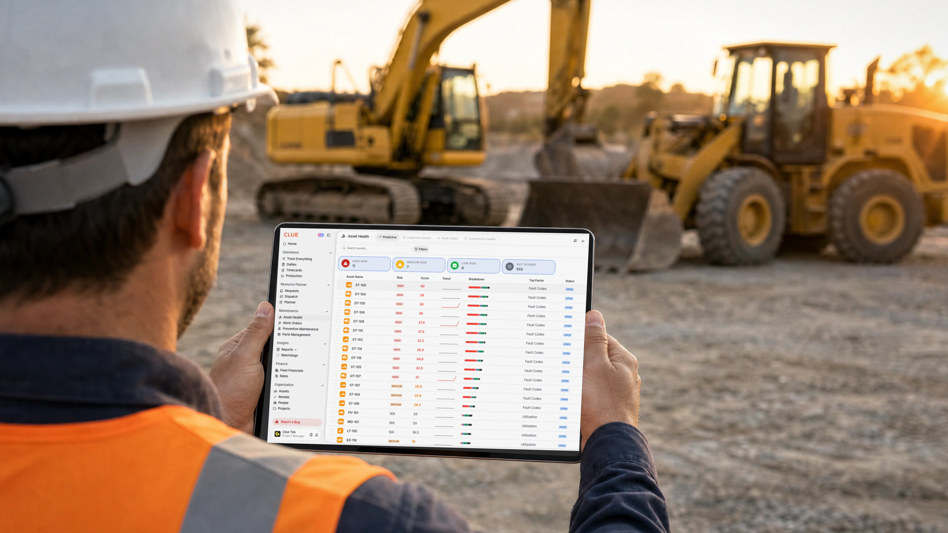 Equipment manager at a jobsite reviewing the Clue Asset Health dashboard on a tablet, where fault codes are the top risk factor on every high-risk machine