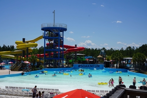 wide view of various slides, wave pool, and chairs at waterpark