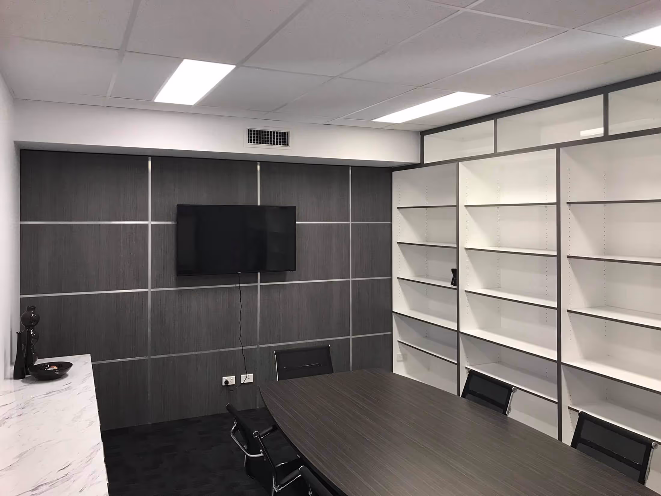 Meeting room with exposed shelves and wall mounted tv