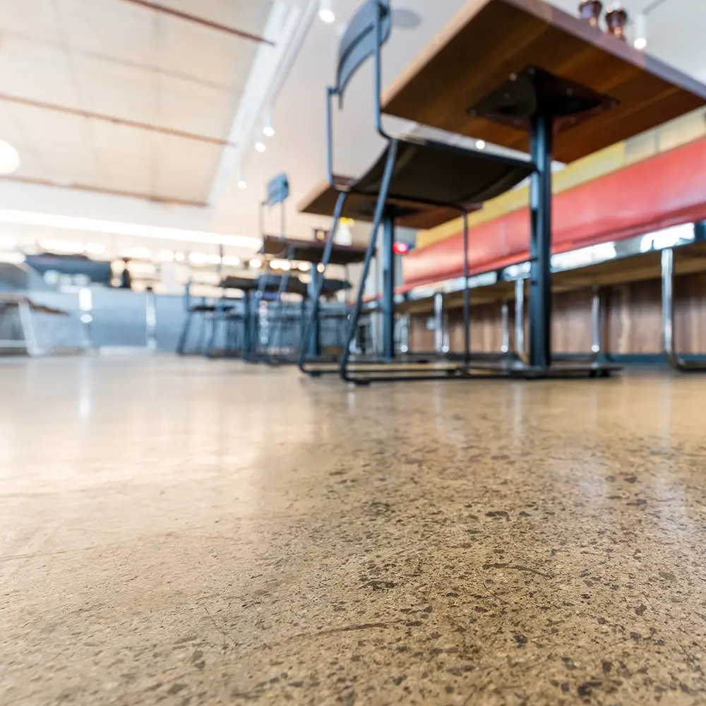 Durable concrete floor surface beneath stools and bench seating in a casual pub setting