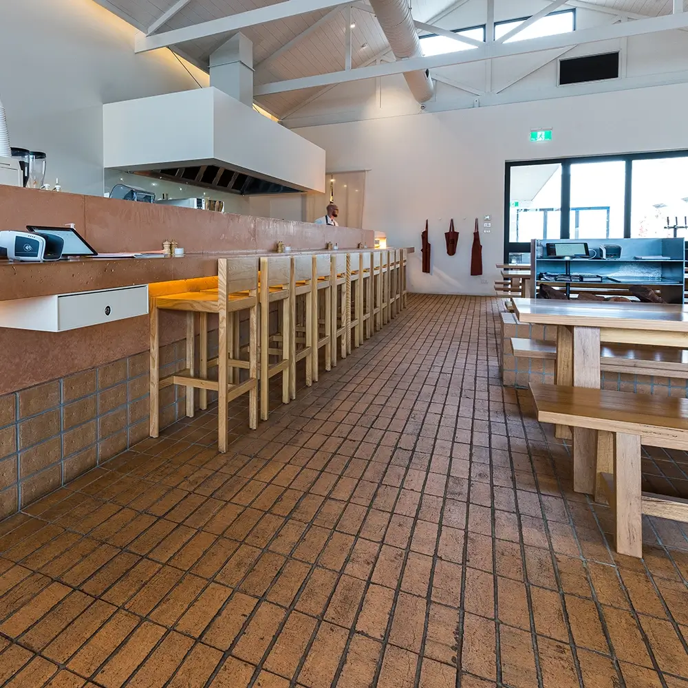 Tiled flooring and long timber bar inside a bright café-style bar with exposed beams