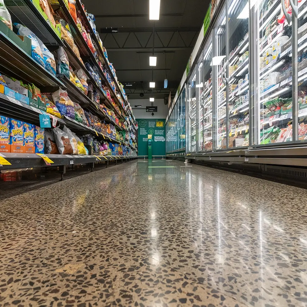 Non-slip polished concrete flooring between refrigerated supermarket aisles.