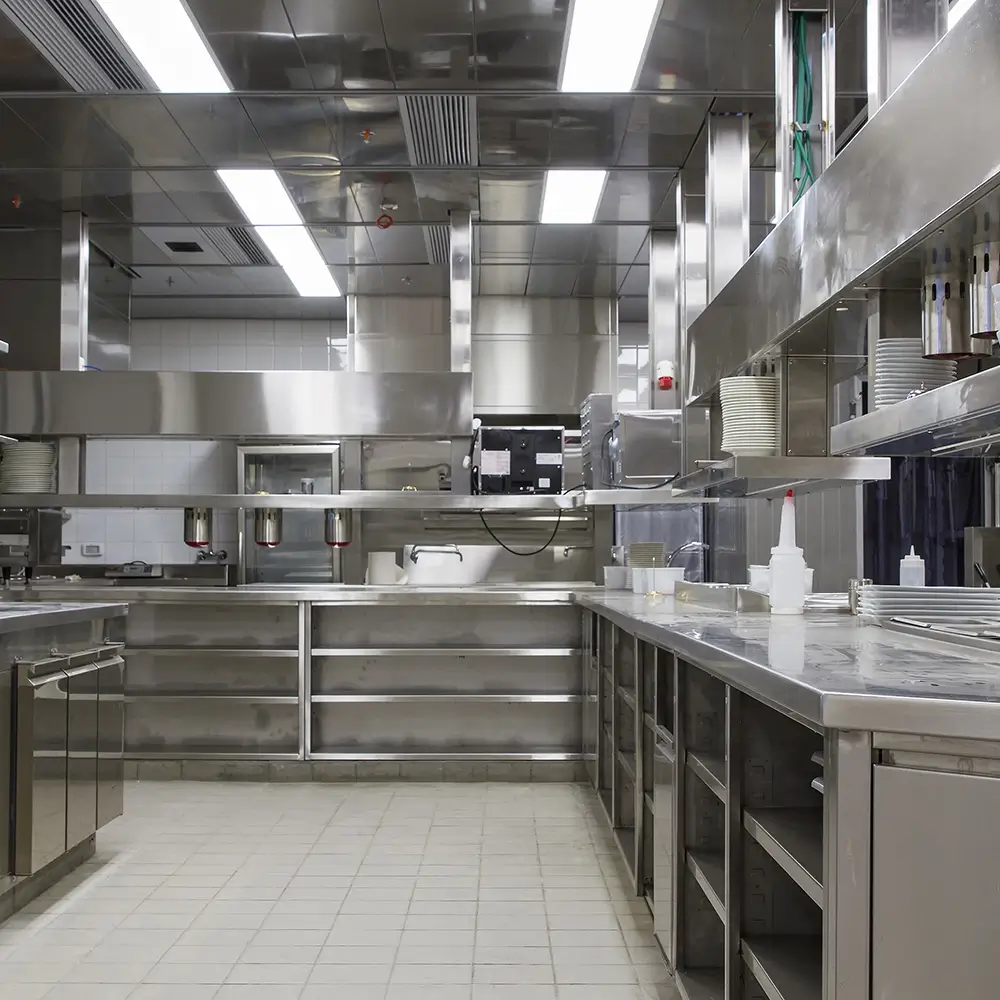 Commercial kitchen with stainless steel surfaces and light-coloured tiled flooring designed for hygiene and durability.