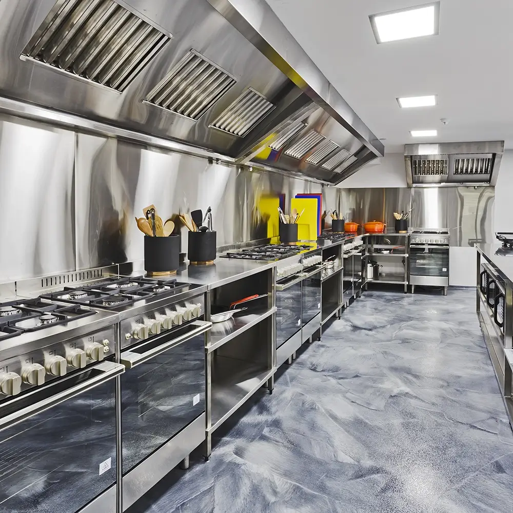 High-end commercial kitchen with stainless steel appliances and blue-toned resin flooring for slip resistance.