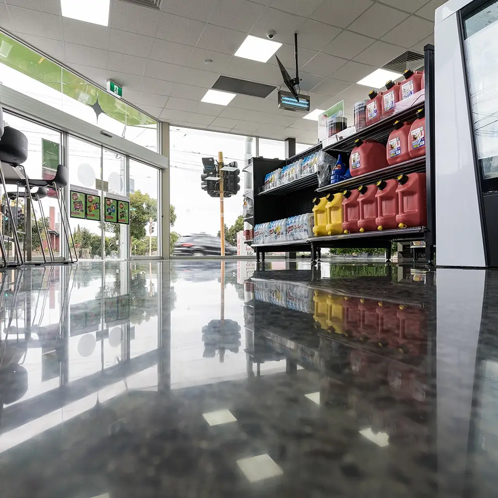 Low-angle view of a retail shop interior showcasing polished flooring, drink fridges, and product displays.
