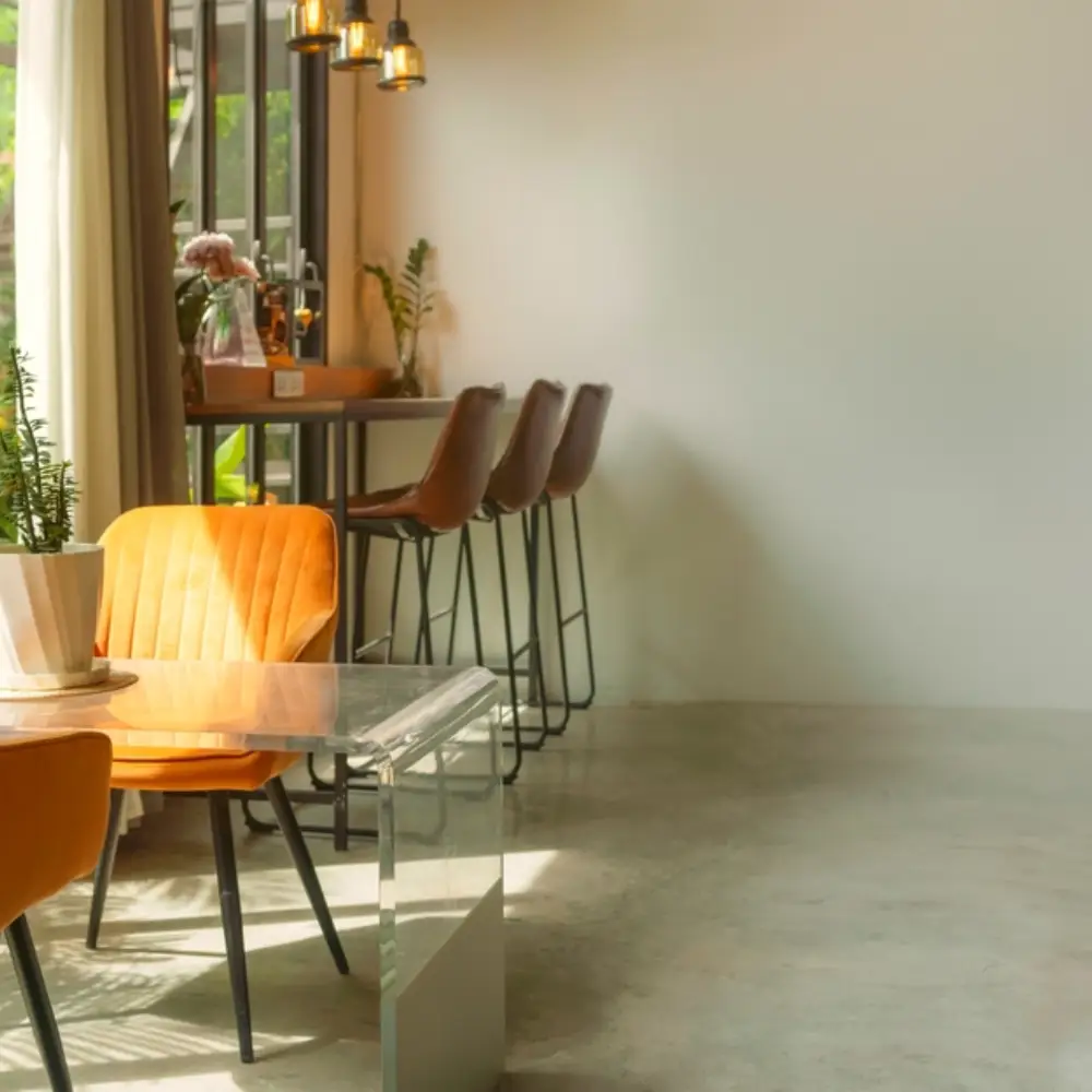Industrial-style polished concrete flooring under a concrete bench with stools in a bright showroom.]