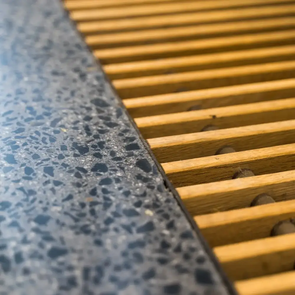 Close-up of polished terrazzo flooring next to a wooden slatted floor vent cover.