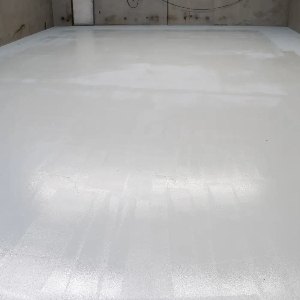 Close-up view of a freshly coated white epoxy floor inside an empty warehouse.