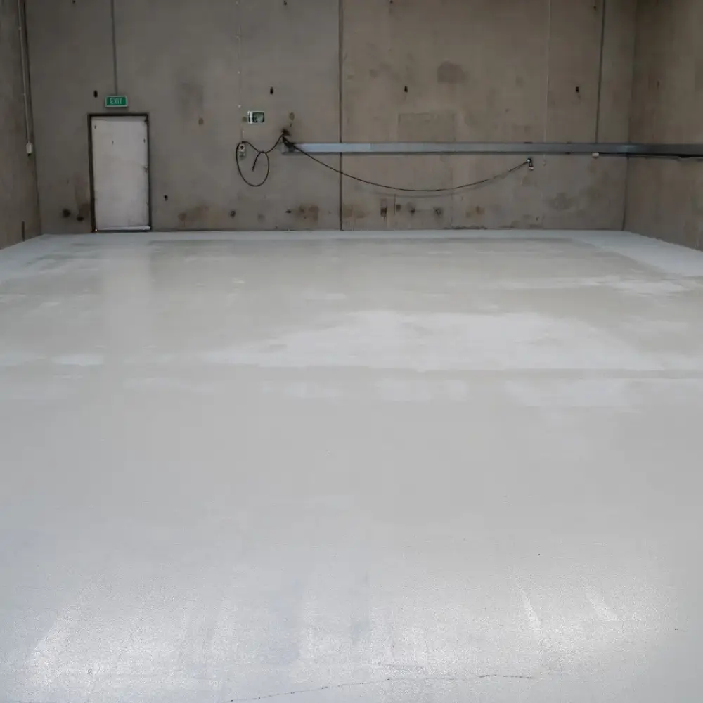 Freshly coated epoxy garage floor with a smooth, glossy finish inside an industrial concrete-walled space.