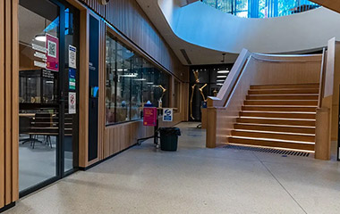 Polished concrete flooring in a modern school with staircase and timber finishes.
