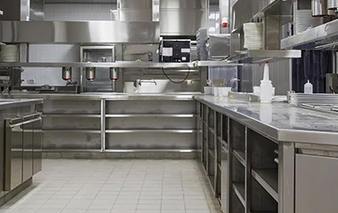 Commercial kitchen with tiled flooring and stainless steel workstations.