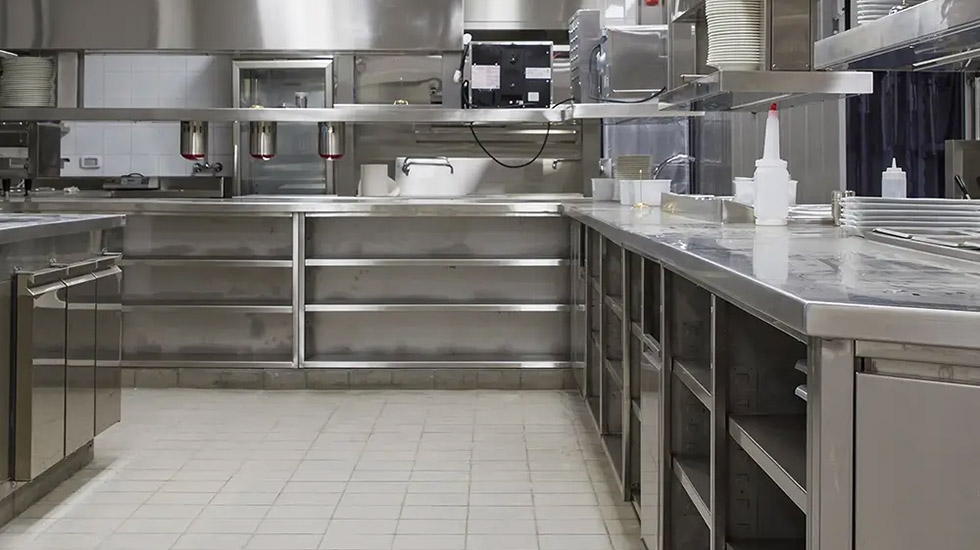 Commercial kitchen with tiled flooring and stainless steel workstations.