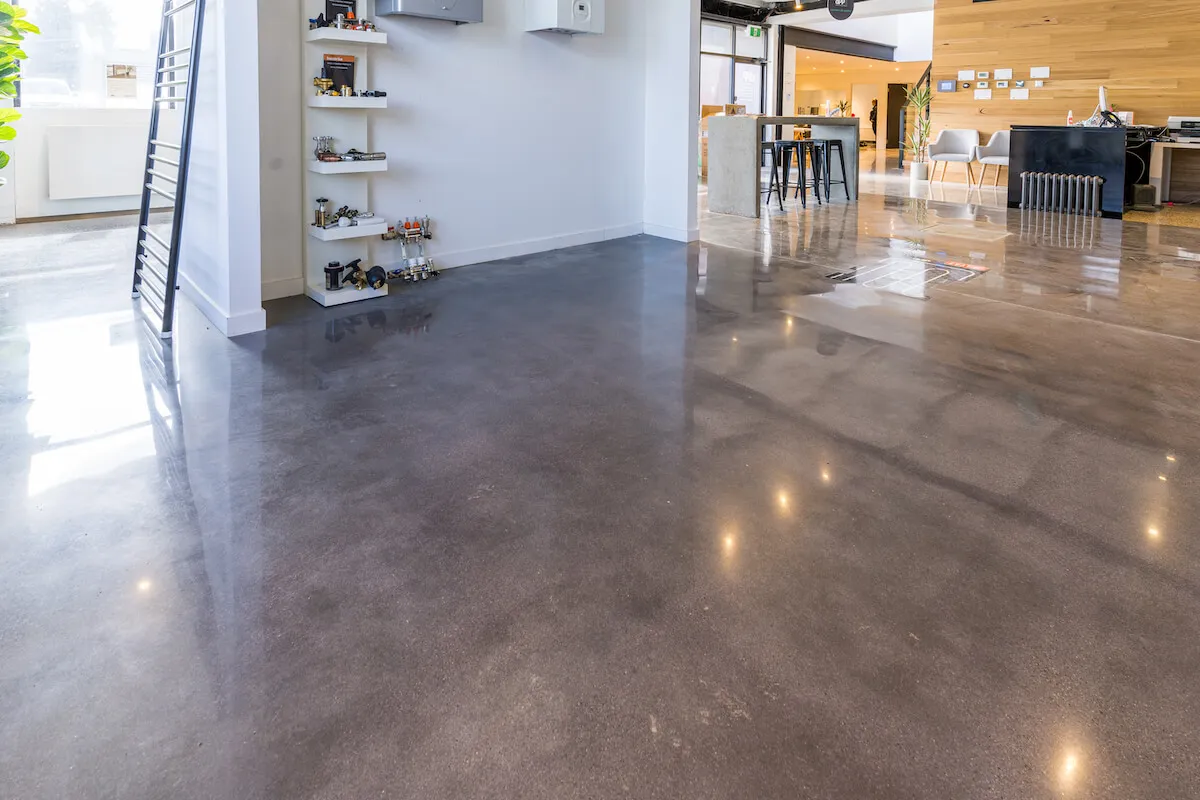 High-gloss polished concrete floors in a modern commercial showroom with industrial shelving and a timber feature wall.