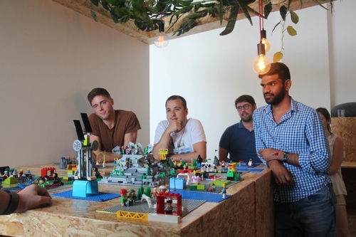 4 Workshop Teilnehmer schauen nachdenklich auf Gebautes aus LEGO®.