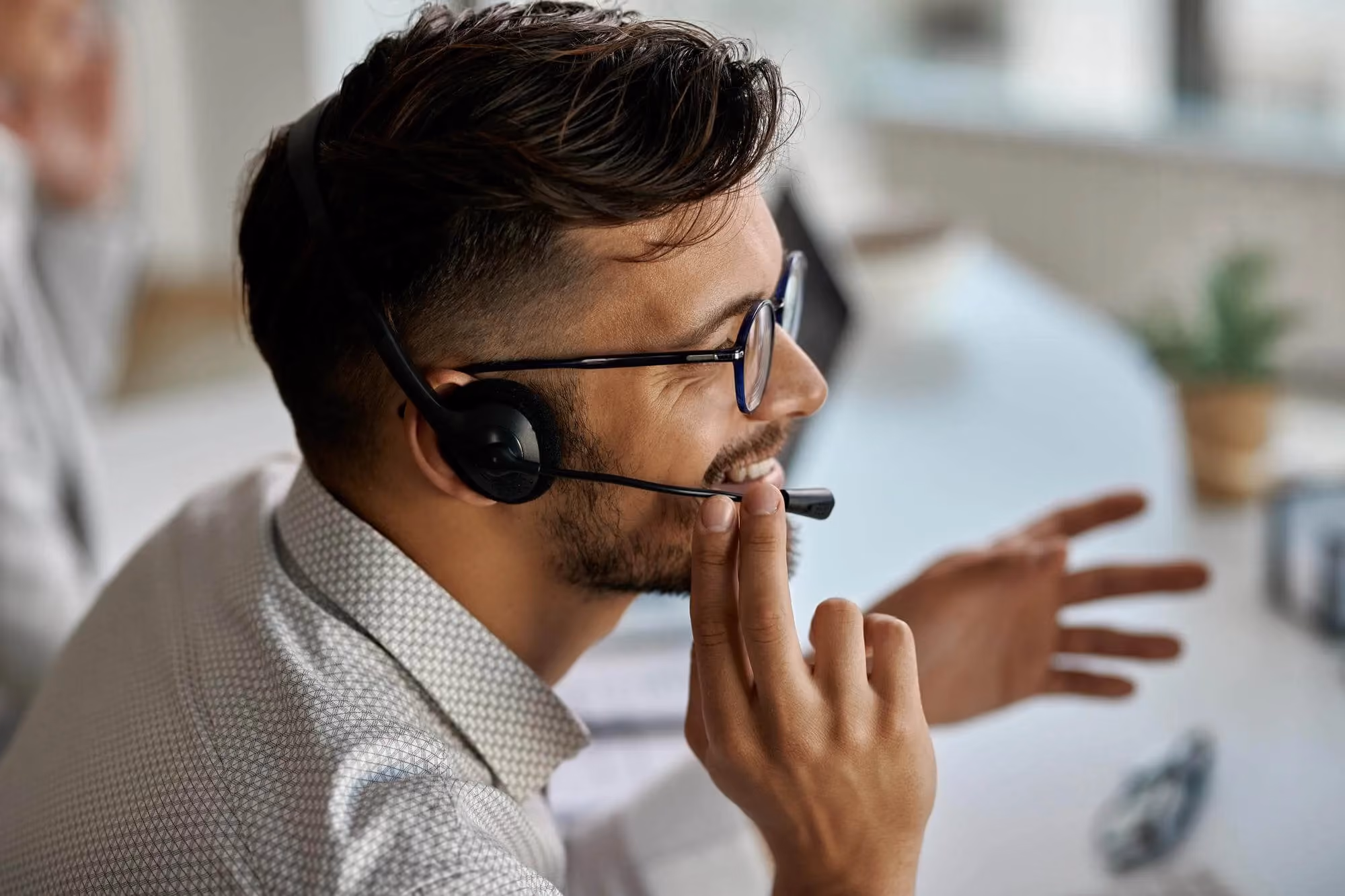 Happy call center agent wearing headset while talking with clients working office