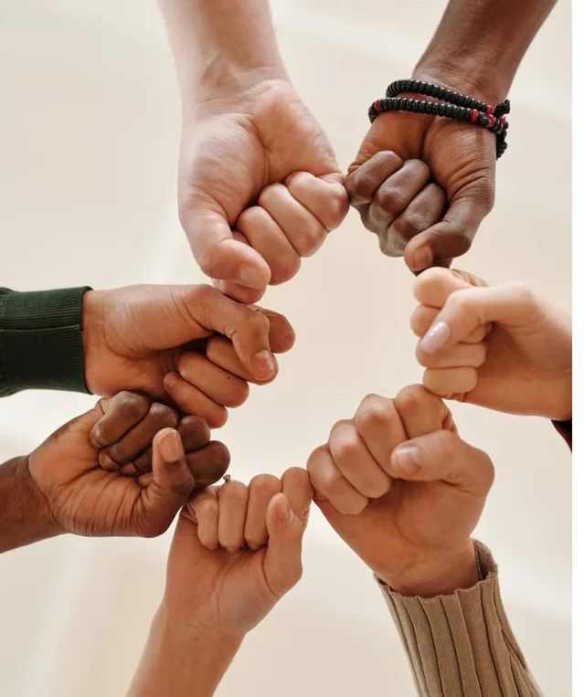 Diverse group of hands joined in a fist bump circle, symbolizing community support