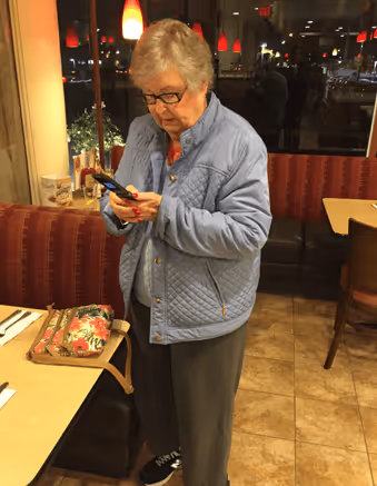 A photo of Grandma Betty in a restaurant calling a ride home via GoGo on her flip phone