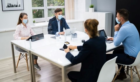 office employees working in a covid safe manner with masks and plastic glass protection to minimise the spread of germs