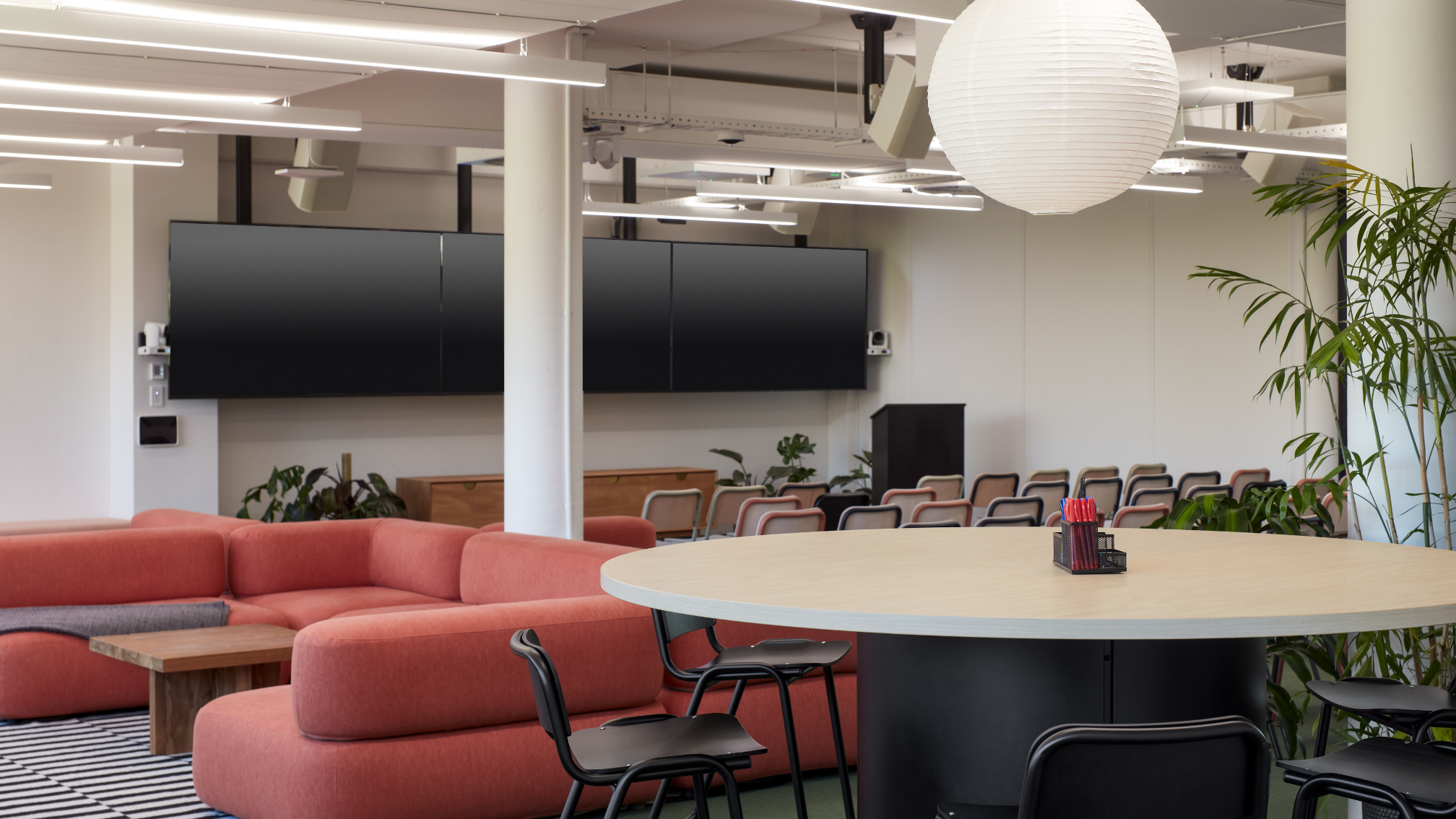 This Zoom Room, built around a Mac Mini, elevates hybrid meetings beyond standard setups. It features 3x front-facing Sony displays and a rear confidence monitor for presenter engagement with both in-room and remote participants. The system includes 5 cameras: 1x AVer CAM340+ for a wide-angle audience view, and 4x AVer PTZ310UV2s for speaker tracking across 6 zones (4 audience, 2 presenter). Custom programming enables seamless camera transitions with pre-loaded views for a smooth, broadcast-style experience. Audio clarity was vital due to room acoustics, achieved through a QSC Core 110f DSP, Lab Gruppen and QSC amplifiers, and Sennheiser TeamConnect 2 ceiling microphones. A key requirement was native Zoom UI control of zoned tracking—without extra menus. Using USB extenders and Wyrestorm NHD500 AVoIP encoders, each camera appeared as an individual source within Zoom, allowing intuitive camera switching and maintaining a high-quality, inclusive experience. Inavate APAC Project Winner for 2025.