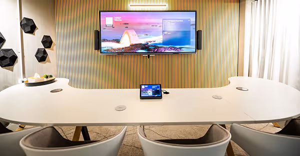 Microsoft Teams Room with wide-format display on wall in front of modern curved meeting table