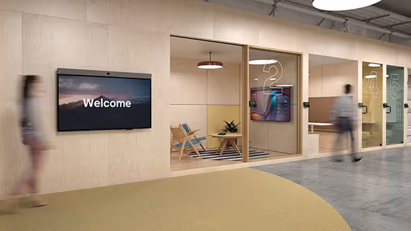 Modern office with digital welcome sign mounted on wall as people walk by