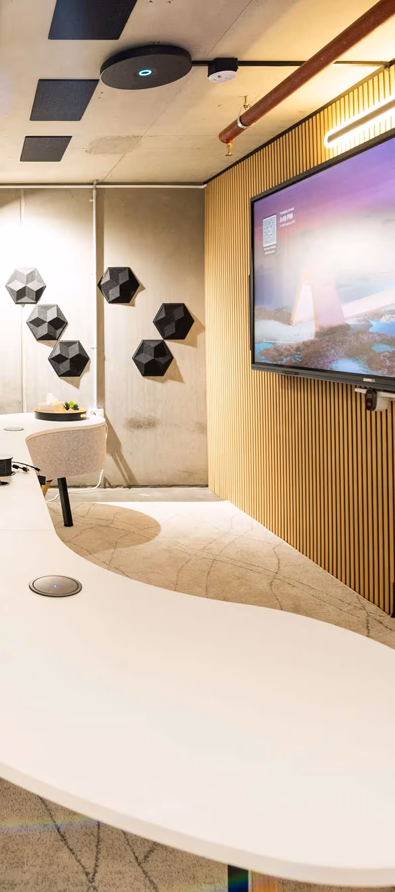 Microsoft Teams Room with wide-format display on wall in front of modern curved meeting table