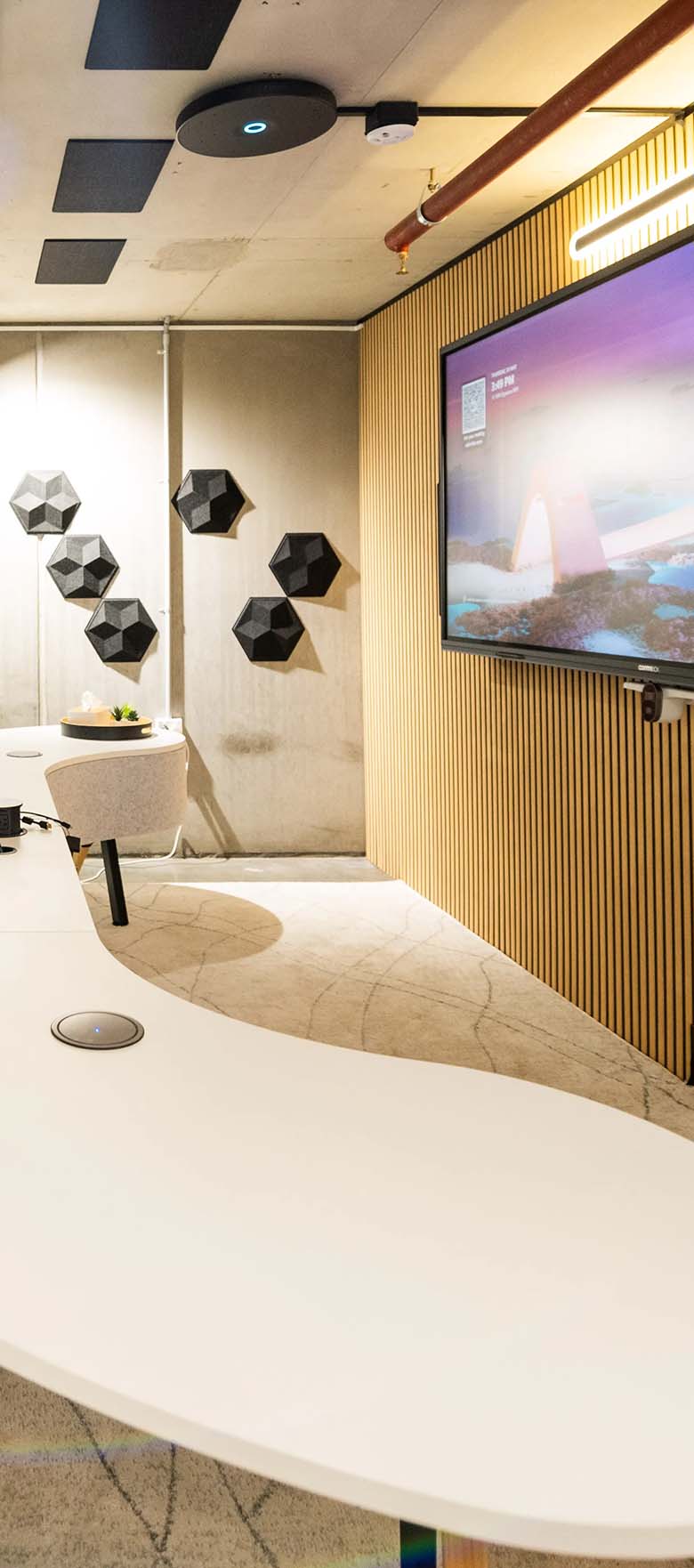 Microsoft Teams Room with wide-format display on wall in front of modern curved meeting table