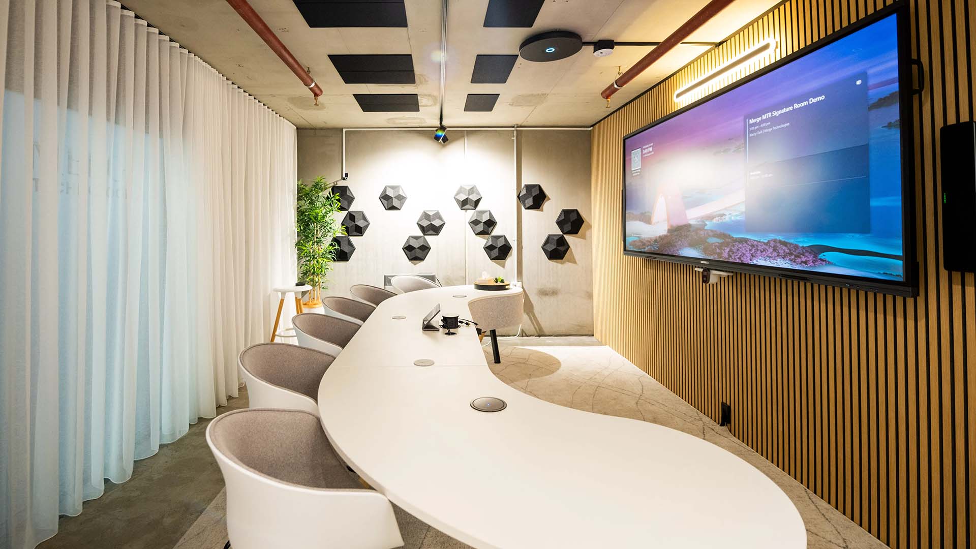 Microsoft Teams Room with wide-format display on wall in front of modern curved meeting table