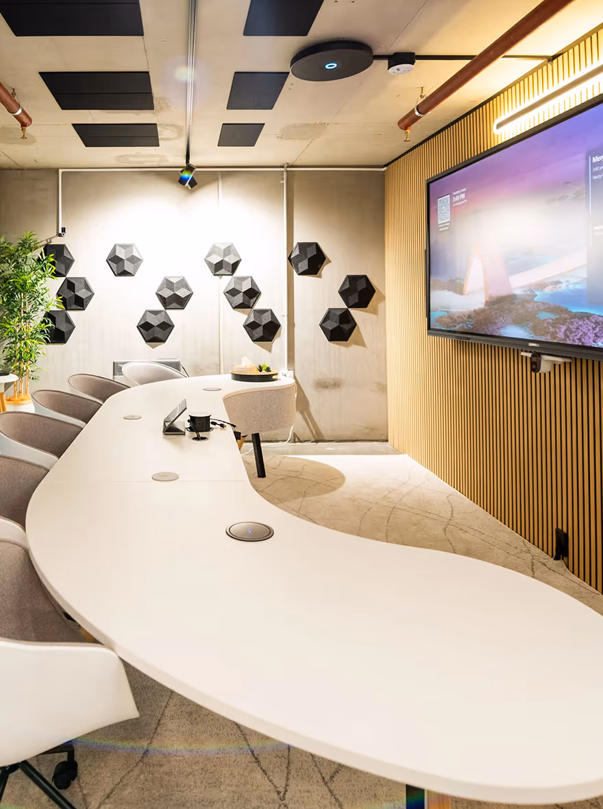Microsoft Teams Room with wide-format display on wall in front of modern curved meeting table