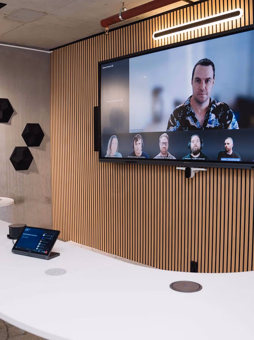 Signature Microsoft Teams Room with large wide-format display, wall-mounted speakers in front of modern curved meeting table.