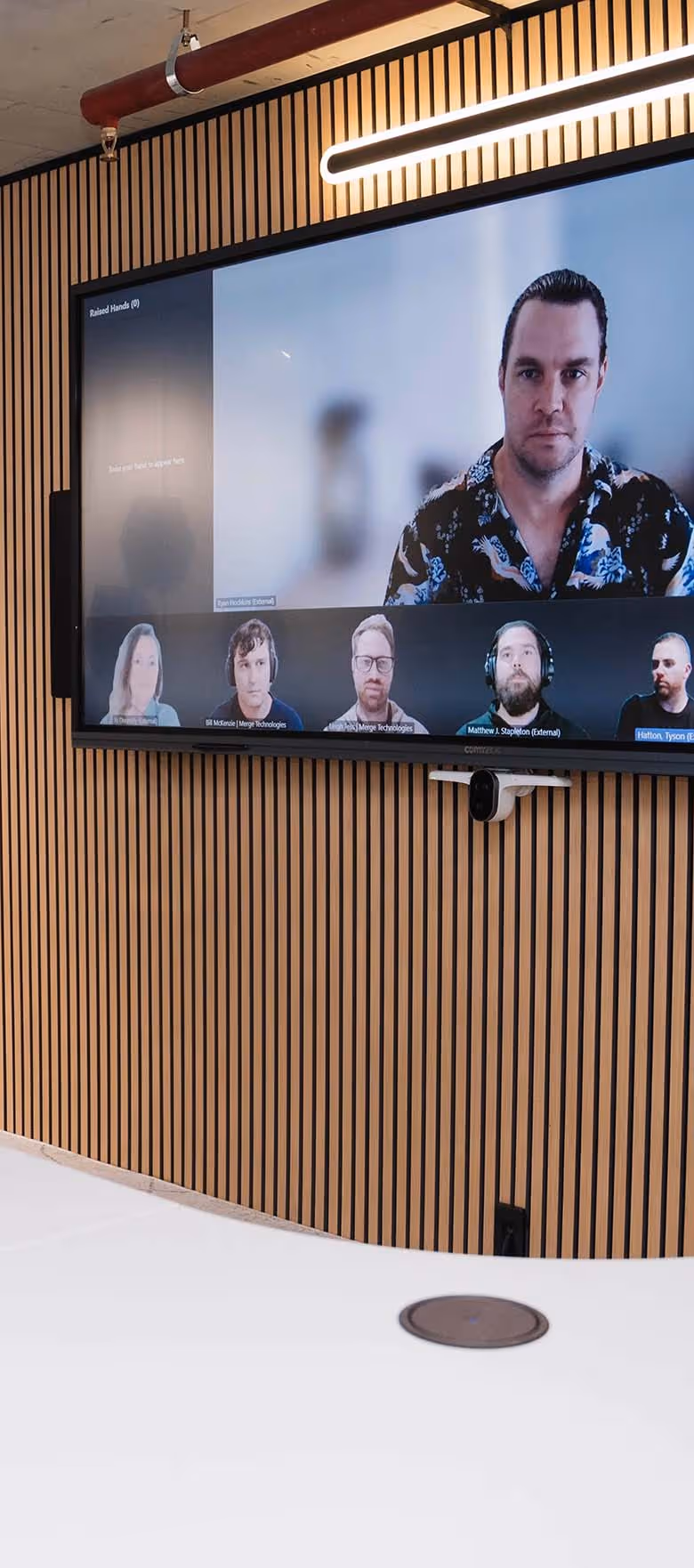 Signature Microsoft Teams Room with large wide-format display, wall-mounted speakers in front of modern curved meeting table.