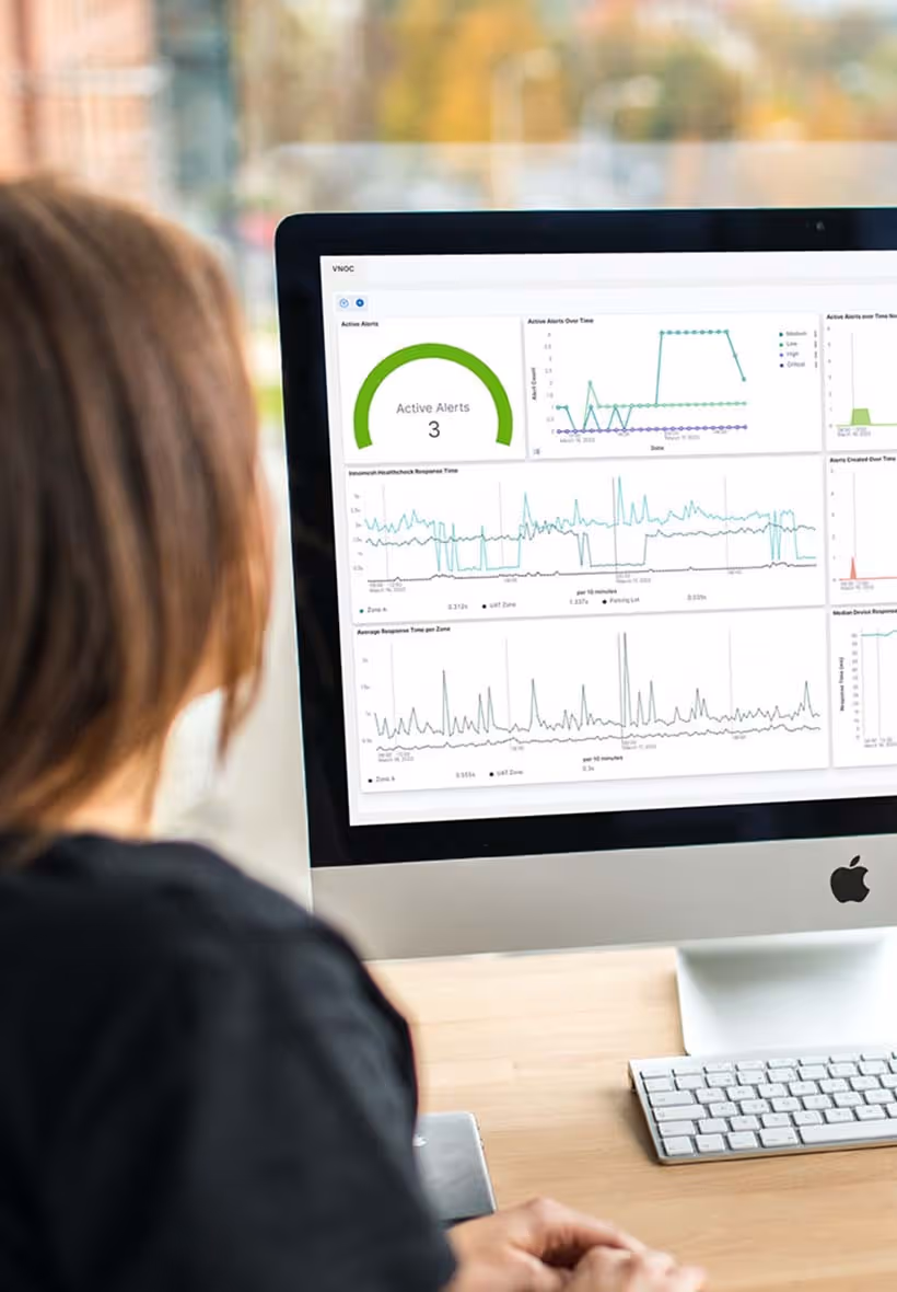Man and woman sitting together in front of desktop monitor reviewing complex data dashboards on screen