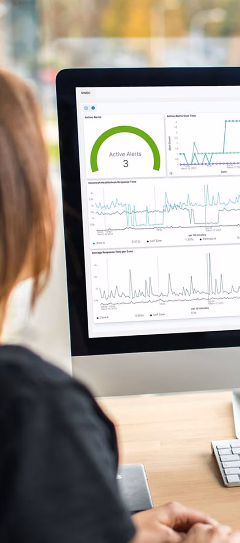 Man and woman sitting together in front of desktop monitor reviewing complex data dashboards on screen
